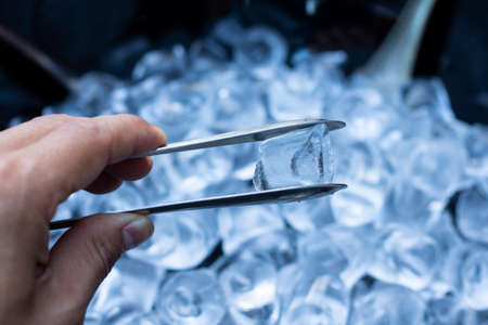 Man using ice clip. Ice cubes Close Up.の写真素材