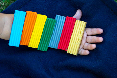 Childs hand holding multi-colored plasticine, flat layの写真素材