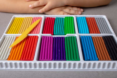 Multi-colored plasticine sticks with sculptural knife, kids hands backgroundの写真素材