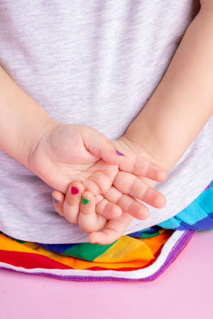 little girl hands with colorful manicure behind back, vertical imageの写真素材