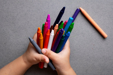 Preschooler holding color wax crayons, selective focusの写真素材