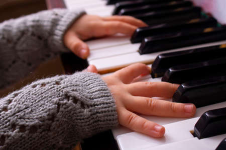 Hands of a little girl trying to play piano musicの写真素材