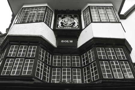 EXETER, UK, 11 July 2016: Facade of an ancient building in the center of Exeter. Mol`s House, 1596. The coat of arms of the city. Black and white photography. Devon. Englandのeditorial素材
