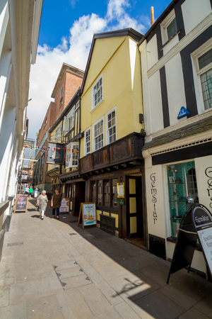 EXETER, DEVON, UK, 22 July, 2016: Narrow street. City center. Two pedestrians walk. Colored houses.のeditorial素材