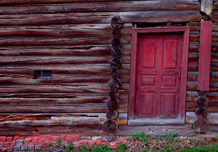 Red door in an old log wall and small windowの写真素材