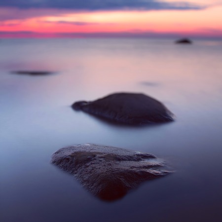 Beautiful seascape at sunset. In the foreground is a large stone. Bokeh. Long exposure.の写真素材