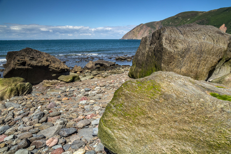 Beach with large boulders at low tide. Boulders covered with algae. In the background you can see the sea. Near the Lynton and Lynmouth villages. North Devon Coast. UKの写真素材
