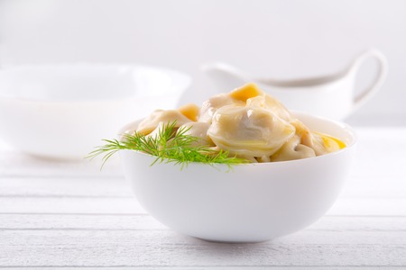 dumplings with butter and dill in white plate on the background of a sauce-boatの写真素材