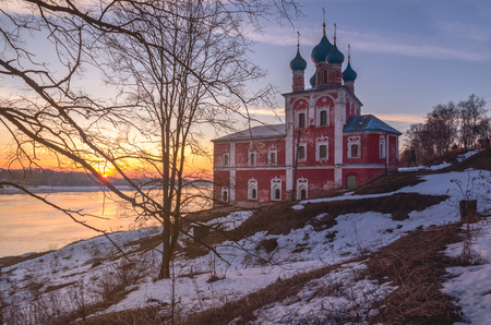 Old stone church of red color on the steep bank of the Volga River. Early spring. Sunset. The city of Tutaev. Yaroslavl region. Russiaの写真素材