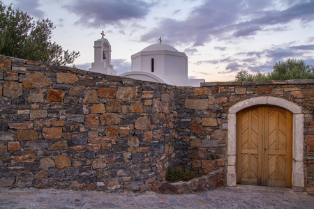 A small white church behind a stone wall. Evening time. The coast of Mirabello Bay. Elounda. Crete. Greeceの写真素材