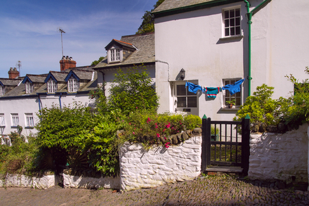 Street with white houses in the village of Clovelly. Three pullovers are dried at the wall of the house on a string. Devon. England.の写真素材