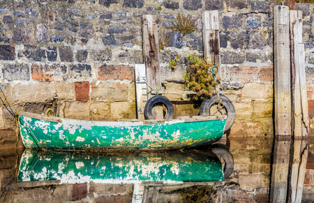 A picturesque old fishing boat is moored near the stone shore. Cockwood. Devon. UKの写真素材