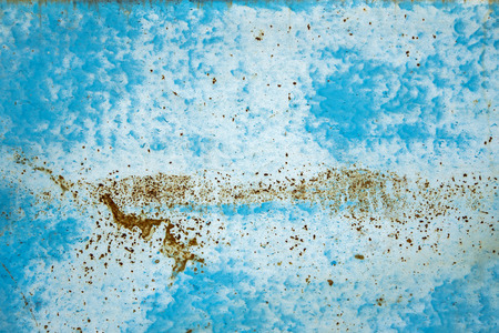 The metal surface is painted in blue. Visible corrosion and stains of paint. Natural backgroundの写真素材