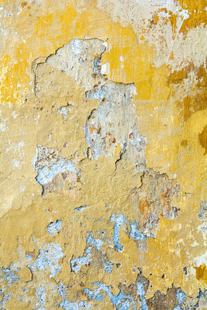 Background. Part of the old wall with peeling plaster. It was painted yellowの写真素材