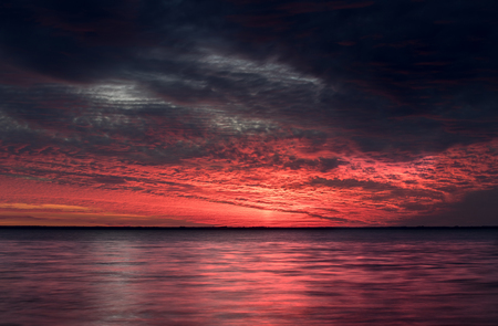 Breathtaking sunset by the sea. Red and blue clouds. The sun has gone down the horizon. Heavenly extravaganzaの写真素材