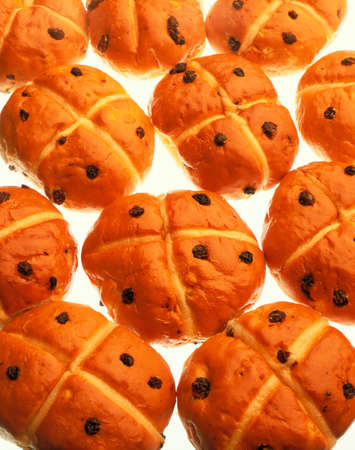 FRESHLY BAKED HOT CROSS BUNS ON WHITE BACKGROUNDの写真素材