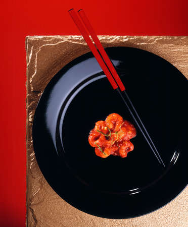 PRAWNS AND RED CHOPSTICKS ON BLACK PLATEの写真素材