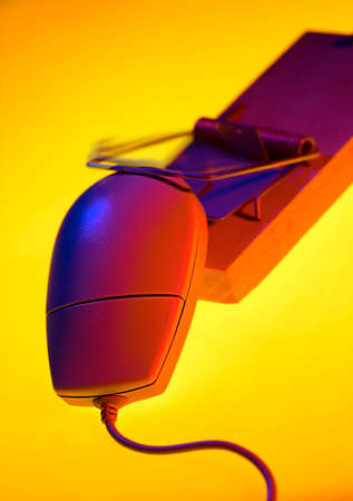 COMPUTER MOUSE TRAPPED IN MOUSE TRAP ON YELLOW BACKGROUNDの写真素材