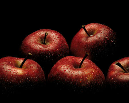 PILE OF FRESH RED APPLES COVERED IN WATER DROPLETS ON BLACK BACKGROUND