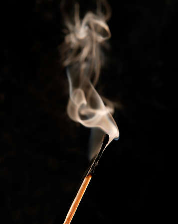 Burning match on black background.