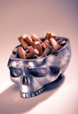 ASH TRAY IN SHAPE OF HUMAN SKULL FULL OF CIGARETTE BUTTSの写真素材
