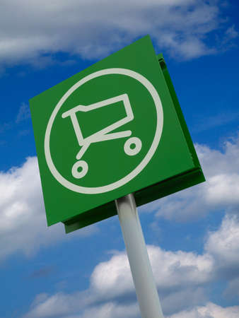 Rectangular sign with painted white icon of supermarket trolly isolated on blue sky and cloud backgroundの写真素材