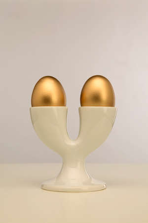Two golden eggs in double white egg cupの写真素材