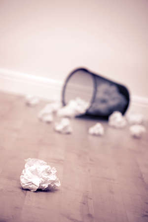 Litter bin on its side with crumpled paper on floorの写真素材