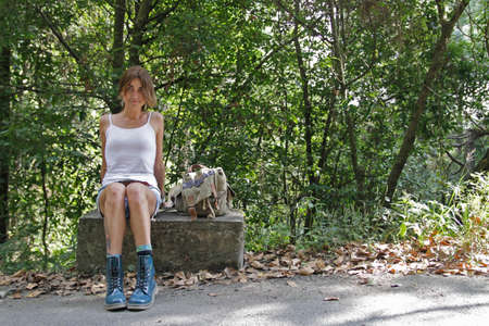 Girl is siting on a side of the roadの写真素材