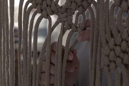 hands weaving knots for a beautiful macramÃ©