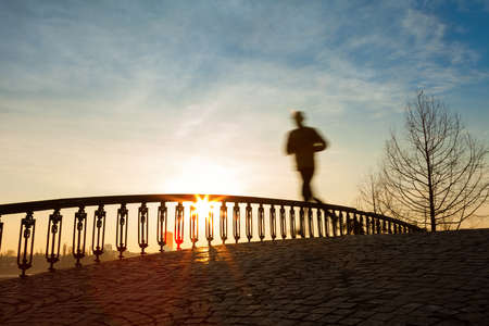 jogger running in sunrise over bridge