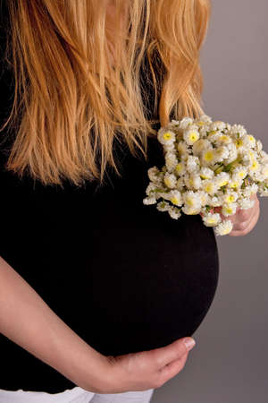 pretty young pregnant blonde with flowersの写真素材
