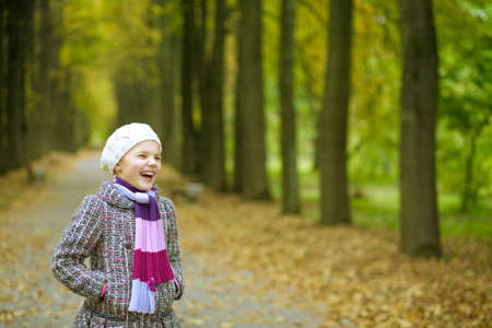 smiling happy cute blonde girl in modern autumn coat having fun in parkの写真素材