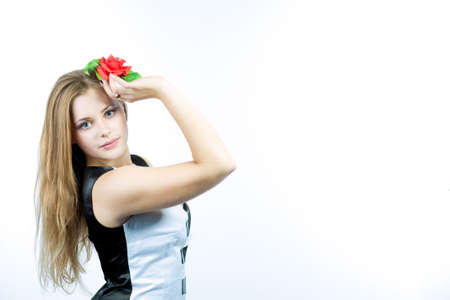 young cute caucasian blond standing in piano like dress holding red flower in hand isolated over white backgroundの写真素材