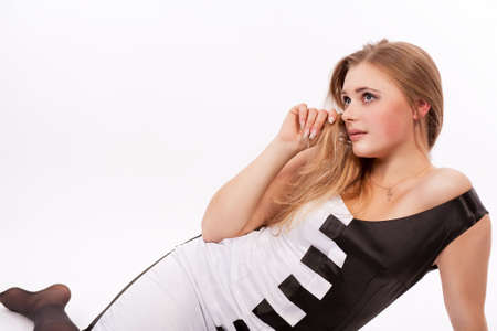 sensual and sexy pretty caucasian blond on floor in piano like dress waiting patiently isolated over whiteの写真素材