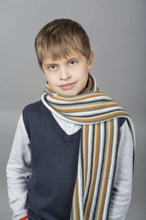 cute and happy young caucasian teenager boy with elegant colorful scarf around and natural light smile standing isolated over gray backgroundの写真素材