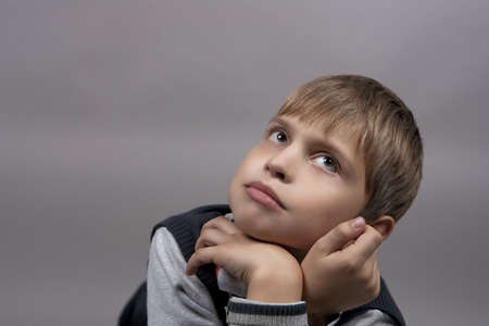 young caucasian blond teenager boy dreaming and looking up isolated over gray backgroundの写真素材