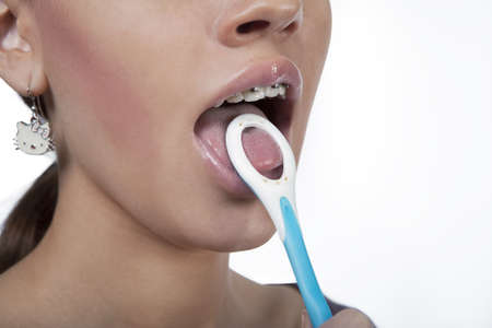 girl cleaning teeth with bracket system using roung toothbrush isolated over whiteの写真素材