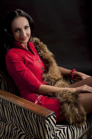 young and pretty brunette caucasian girl in passionate red dress sitting on striped chairの写真素材