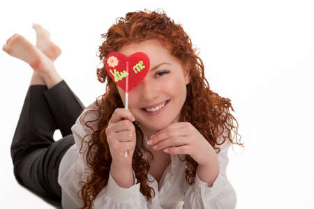 happy laughing young red haired girl with heart-looking candy lying and relaxing with natural beautiful smile isolated over whiteの写真素材
