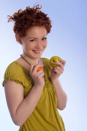caucasian girl with positive natural smile making choice between two types of fruits isolatedの写真素材