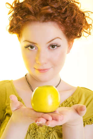 young beautiful girl with green apple on hands standing with pleasant smile isolatedの写真素材