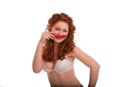 young and sexy caucasian girl in lingerie having fun with chili pepper standing with shaped body...
