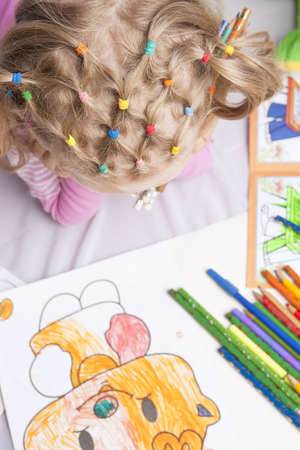 pretty and unique hair tails of young blond caucasian girl thinking and making picture with pencilsの写真素材