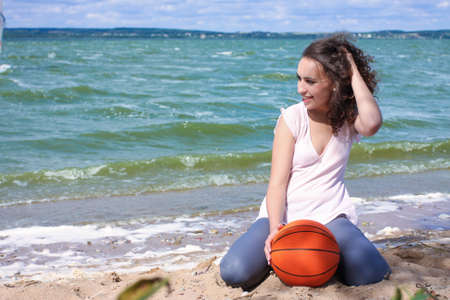 sporty and slim caucasian girl with curly natural hair laughing and resting near seaの写真素材