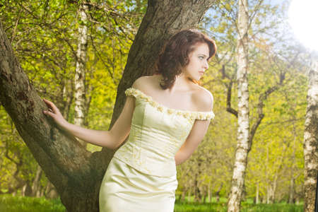 portrait of a sensual  brunette caucasian girl in wedding dress standing in spring forest-outsideの写真素材