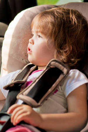 portrait of little kid in safety seat looking through window pan