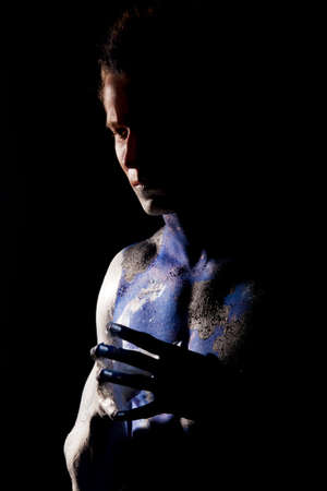 profile of handsome caucasian man with body-art mozaic painting standing against black background: part of body-art projectの写真素材