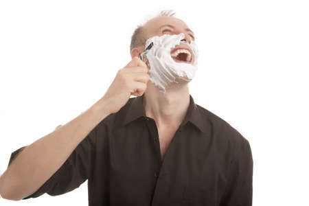 portrait of a funny young caucasian man shaving his beard with razor, standing isolated over white backgroundの写真素材