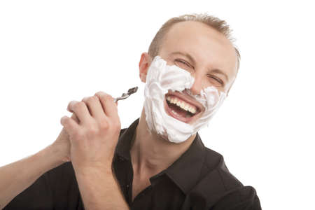 portrait of a funny young caucasian man shaving his beard with razor, standing isolated over white backgroundの写真素材